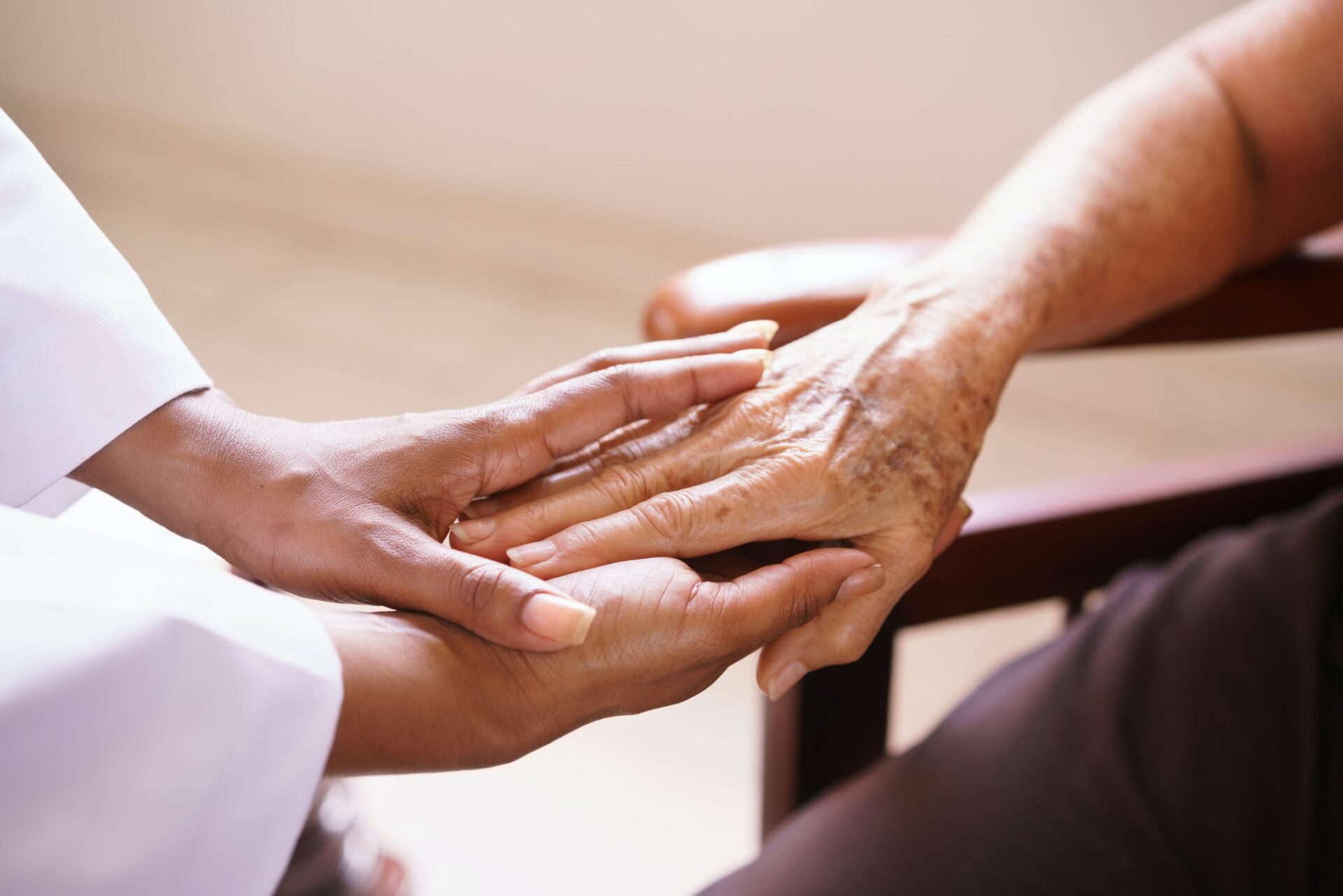 Senior Woman And Hospice Worker Holding Hands As They Talk